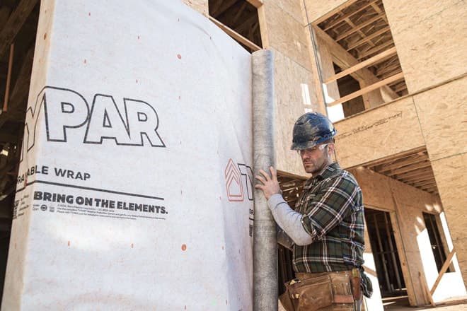Construction worker installs hydrogap house wrap to home